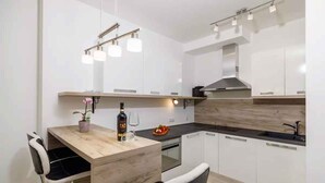 A modern kitchen with white cabinets, a wooden dining table, and bar stools.