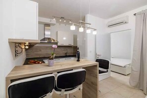 A modern kitchen with a wooden countertop, two black chairs, and a dining table. There is a built-in stove, a sink, and a window with curtains. - Holiday flat with pool (Crikvenica)