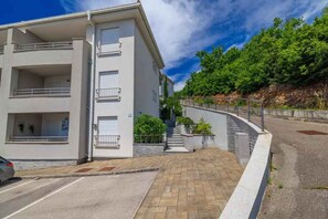 A modern multi-story building with balconies, a paved driveway, and a staircase leading to the entrance. - Holiday flat with pool (Crikvenica)