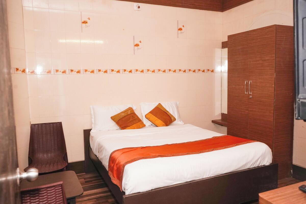 A hotel room with a bed, a wardrobe, a chair, and a desk.