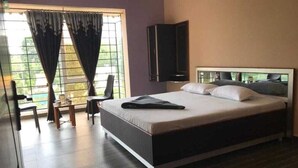 A modern bedroom with a large bed, a TV mounted on the wall, and a window with curtains. - Hk Grand Inn By K Hotels (Yercaud)