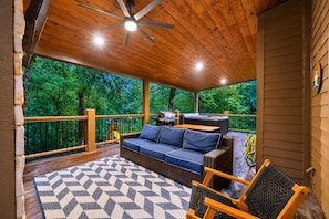 A covered outdoor deck with a ceiling fan, a sofa, a table, and a grill. - Family Escape | Hot Tub + Playset | Sleeps 10 (Broken Bow)