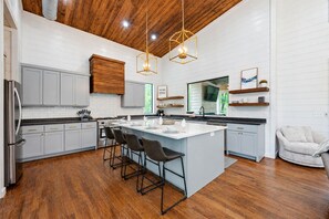 A modern kitchen with a central island, bar stools, and wooden cabinetry.