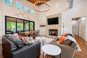 A spacious living room with a fireplace, a dining area, and a seating arrangement. - Family Escape | Hot Tub + Playset | Sleeps 10 (Broken Bow)