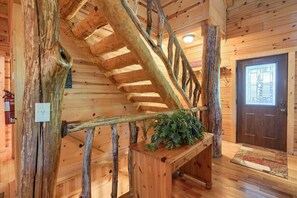 A wooden staircase with a rustic design, a wooden door, and a plant on a wooden table.