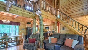 Ein geräumiges Blockhauskabinett mit einer Holztreppe, einem Essbereich und einem Wohnzimmer mit Sofa und Sesseln.