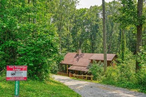 A rustic lodge with a wooden cabin and a covered porch, surrounded by dense forest.