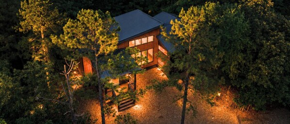 A cabin surrounded by trees with a wooden deck and a covered outdoor area. - Central Location! 3BR Cabin Hot Tub + Playset (Broken Bow)