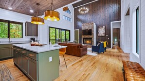 A spacious kitchen with a large island, wooden floors, and a fireplace.