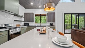 A modern kitchen with a large island, stainless steel appliances, and dark cabinetry.