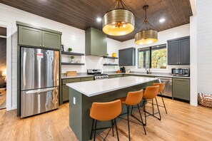Una cocina moderna con una isla central, electrodomésticos de acero inoxidable y techo de madera.