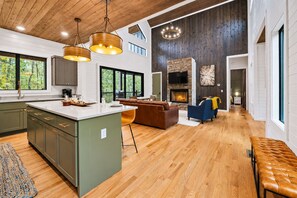 Un amplio espacio habitable con una isla grande, una chimenea y vistas al exterior.