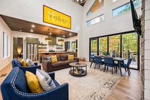 A spacious living area with a large sofa, a dining table, and a kitchen in the background.