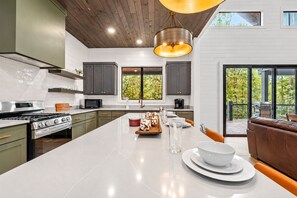 Una cocina moderna con una isla central, electrodomésticos de acero inoxidable y vistas al exterior.