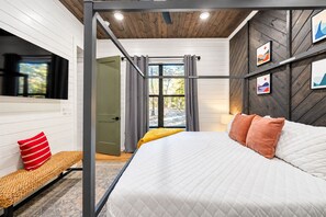 Un dormitorio con cama, una banca, una ventana y una puerta.