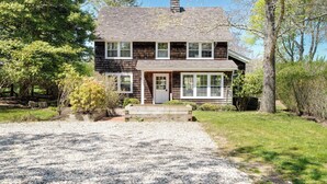 Ein zweistöckiges Haus mit Kiesauffahrt und einer Veranda.