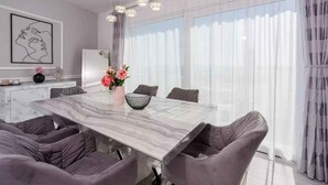 A modern dining area with a marble table, cushioned chairs, and a vase of flowers. - Holiday apartment with balcony (Crikvenica)