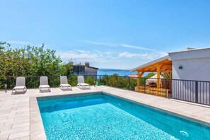 A swimming pool with lounge chairs and a view of the sea. - Holiday apartment (Crikvenica)