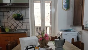 Un coin repas avec une table dressée pour deux personnes, une machine à café, un panier de collations et une fenêtre donnant sur un beau paysage.