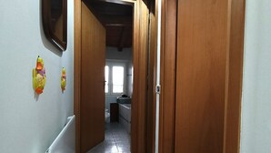 Un couloir avec des portes en bois, un sol carrelé et un ventilateur de plafond.