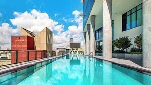 An outdoor swimming pool with clear blue water, surrounded by modern architecture and a clear sky. - Modern Lux Condo in The Biscayne Bay #2301 (Miami)