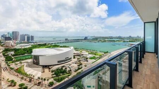 A high-rise building with a panoramic view of a coastal cityscape, including a distinctive round building and a bridge. - Modern Lux Condo in The Biscayne Bay #2301 (Miami)