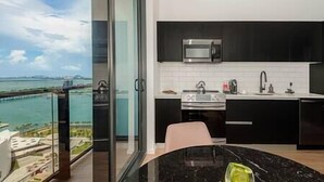 A modern kitchen with a view of the sea, a dining area, and a large window. - Lux Studio with Bay Views #3104 (Miami)