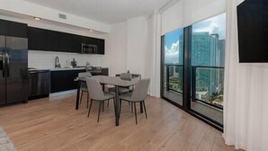 A modern kitchen with dark cabinetry and a dining area with a table and chairs. - Lux 2 BD Condo at The Biscayne Boulevard #3009 (Miami)