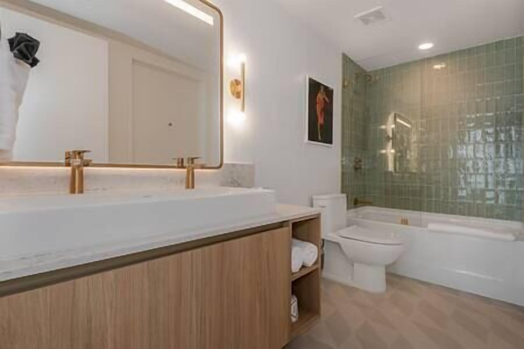 Une salle de bain moderne avec un meuble-lavabo en bois, un grand miroir, des toilettes et une baignoire.