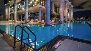 Un espace piscine moderne avec une piscine à eau claire, des chaises longues et un escalier menant à l’intérieur du bâtiment.