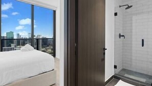 Une chambre d’hôtel moderne dotée d’une grande fenêtre, d’un lit et d’un espace douche.