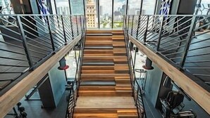 Un escalier avec des marches en bois et des rampes en métal, menant à l’étage supérieur.