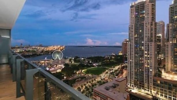Um edifício alto com vista para um parque e um corpo de água.