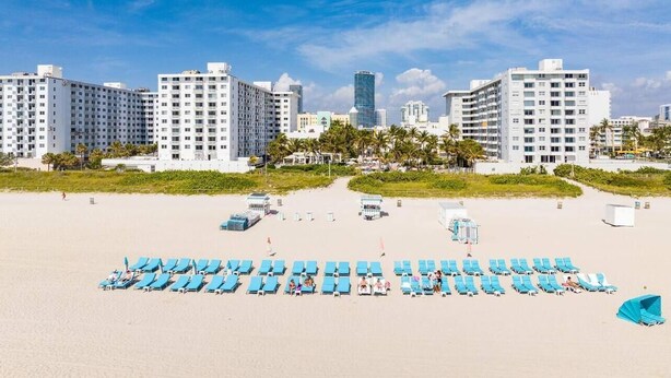 A beach with rows of blue lounge chairs and a cityscape in the background. - Classy 3BD in Downtown Miami - #2618 (Miami)