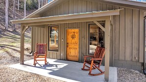 A wooden cabin with a porch, two rocking chairs, and a large wooden door. - Mtn Cabin with Creek Views and Waterfall (Cosby)