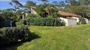 Une maison avec un toit en tuiles, entourée de verdure et sous un ciel dégagé.