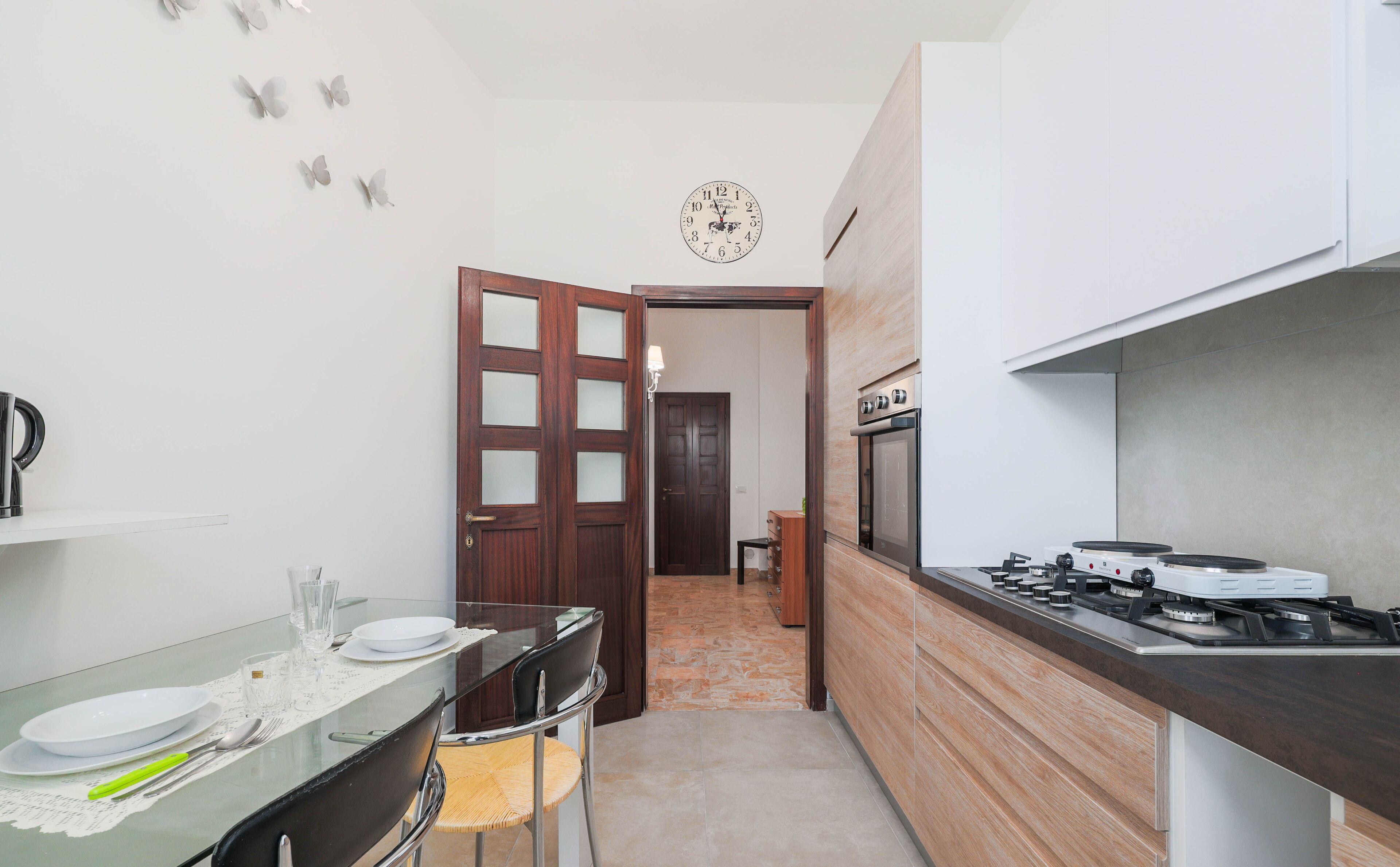Cocina compacta con estufa a gas, una mesa de comedor con platos y cubiertos, y un armario de madera.