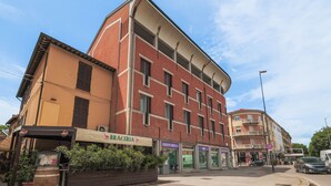 A multi-story building with a red brick facade, a ground-level restaurant, and a medical center on the ground floor. - The prestigious corner of Forli (Forlì)
