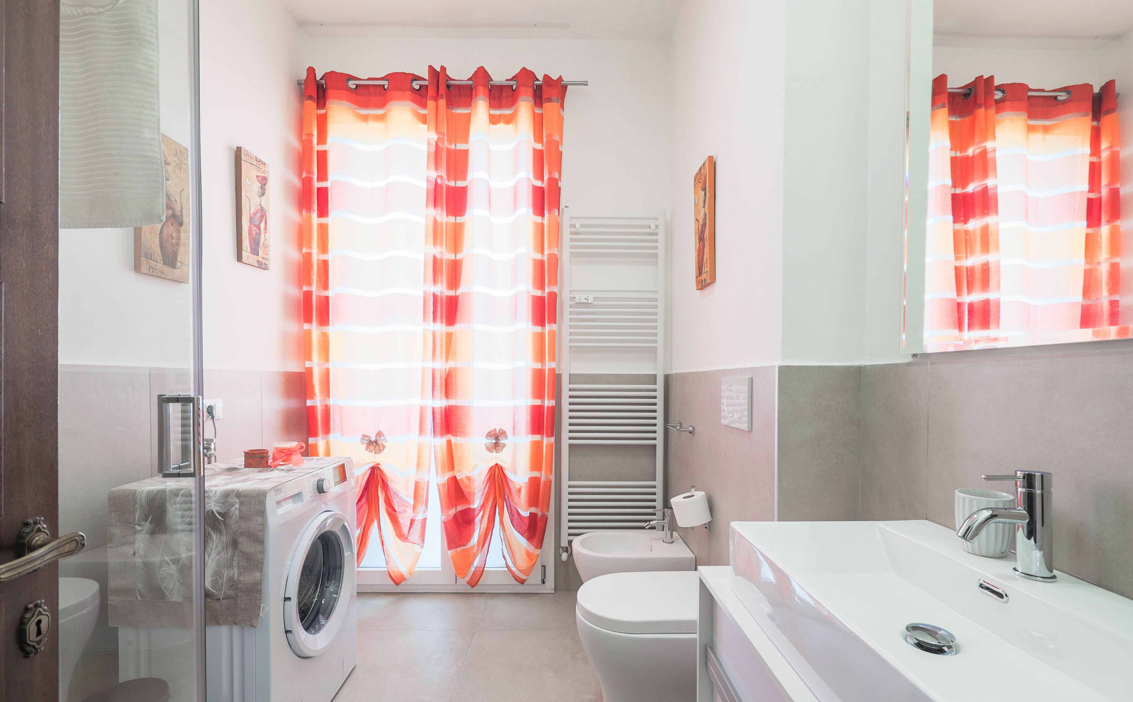 Une salle de bain équipée d’un lave-linge, de toilettes et d’un lavabo.