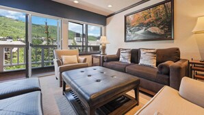 A spacious living room with a large window, a sofa, a chair, and a coffee table. - Saint James Place 214 (Beaver Creek)