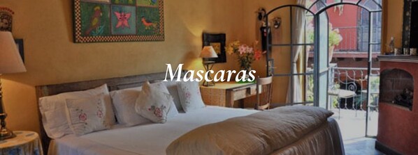 Habitación de hotel con cama, almohadas, mesita de noche, lámpara, un cuadro y vistas al exterior.