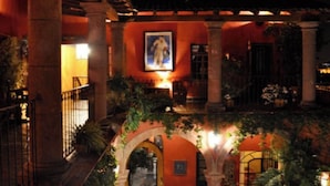 An indoor courtyard with arches, columns, and a mural. - Casa de la Cuesta Bed and Breakfast (San Miguel de Allende)