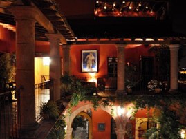 Un patio interior con arcos, columnas y un mural.