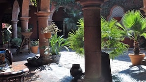 An outdoor courtyard with stone columns, potted plants, and a tiled floor. - Casa de la Cuesta Bed and Breakfast (San Miguel de Allende)