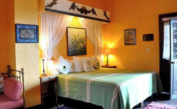 A bedroom with a bed, a nightstand, a chair, and a door.