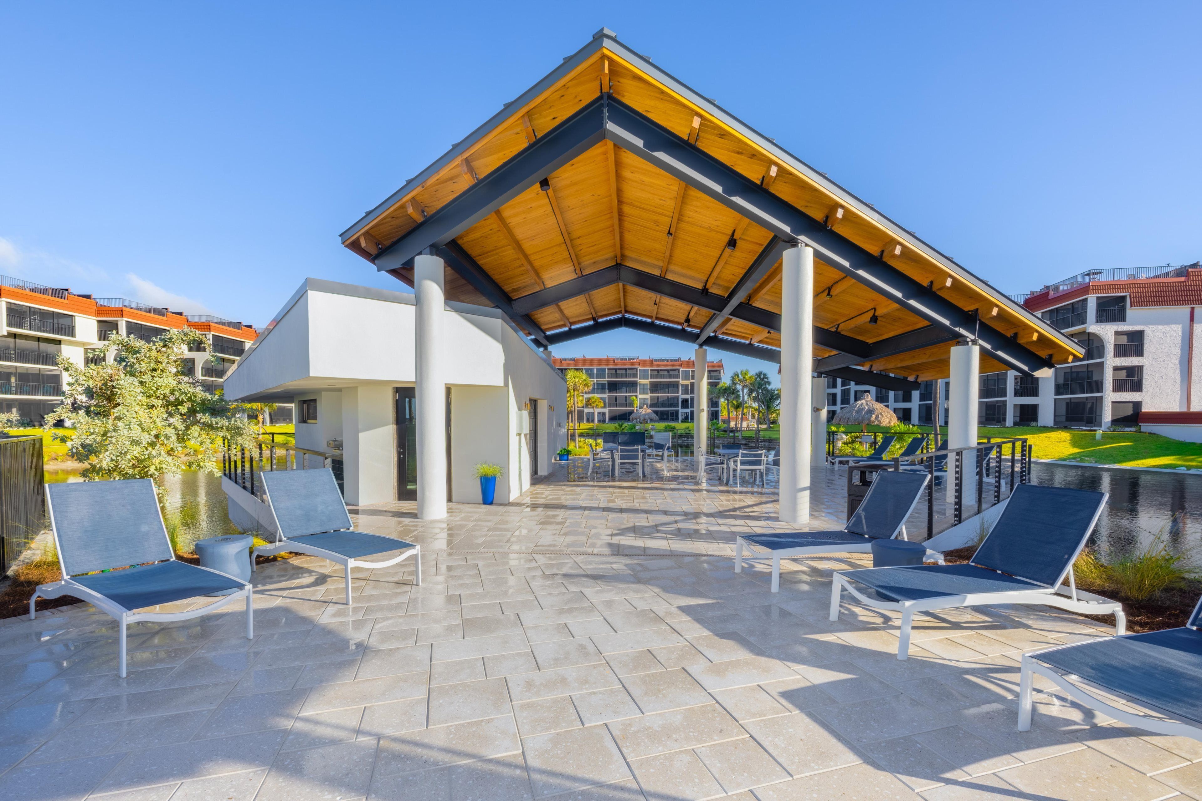 Ein überdachter Außenbereich mit Liegestühlen, einem Pool und einem Gebäude im modernen Stil.