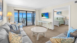 Une chambre d’hôtel avec un balcon, une table ronde, un lit et un téléviseur.