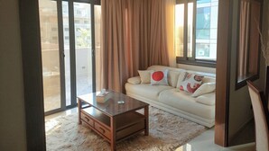 Un salon comprenant un canapé, une table basse et une porte-fenêtre coulissante donnant sur un balcon.