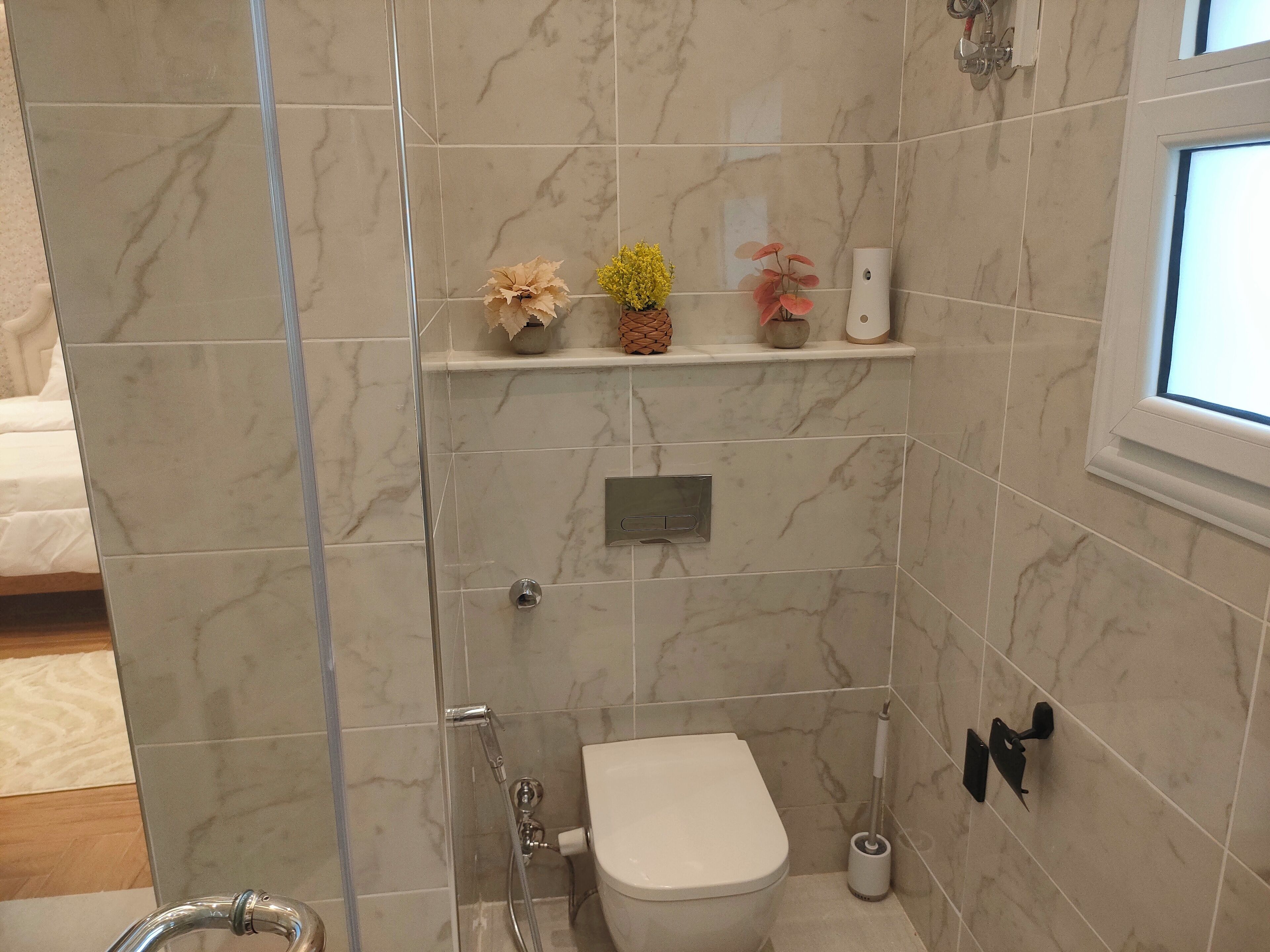 Een badkamer met toilet, douche en een plank met decoratieve objecten.