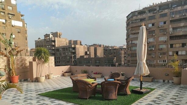Une terrasse sur le toit, aménagée avec des meubles en osier, des plantes en pot et un parasol.